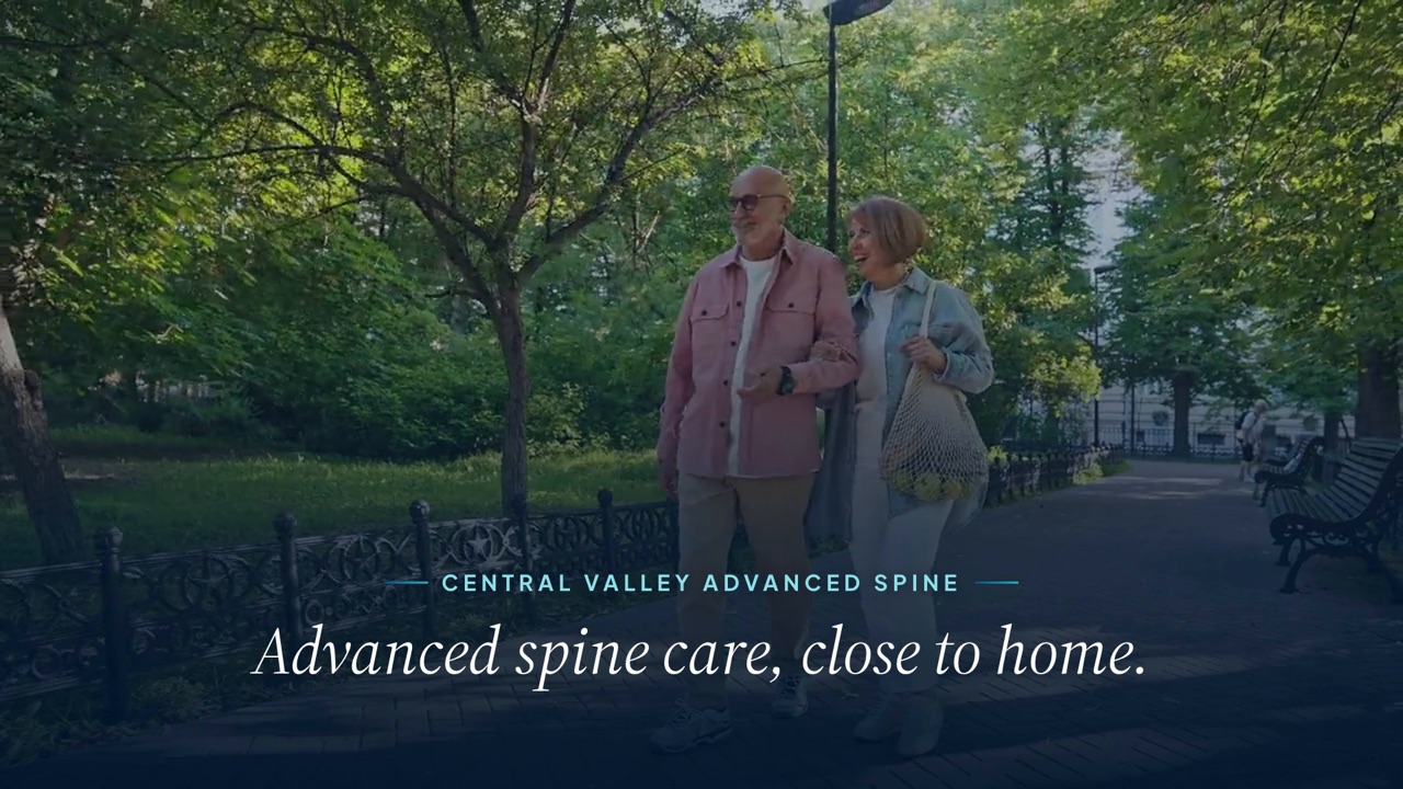 Video still of an older couple walking arm in arm through a park, with the words Advanced spine care, close to home